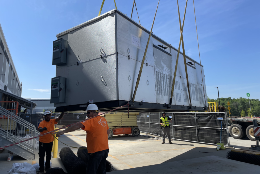 3 CoolSys technicians in PPE outside, lowering new equipment from crane onto rooftop